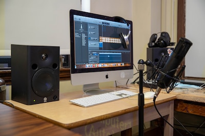A desktop computer with music recording equipment on a wooden desk.