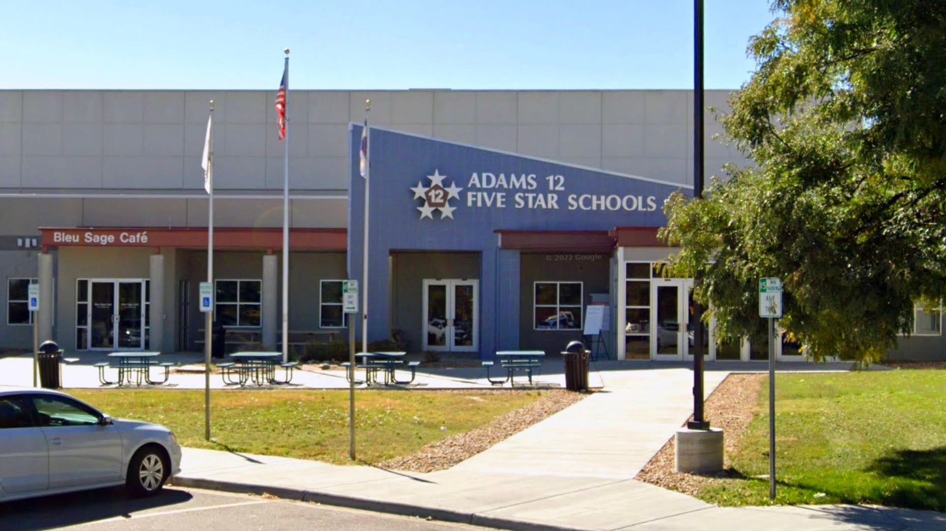 Photo shows Adams 12 Five Star Schools district offices in Thornton. The blue entryway has a sharp angle with a large sign with the district name.