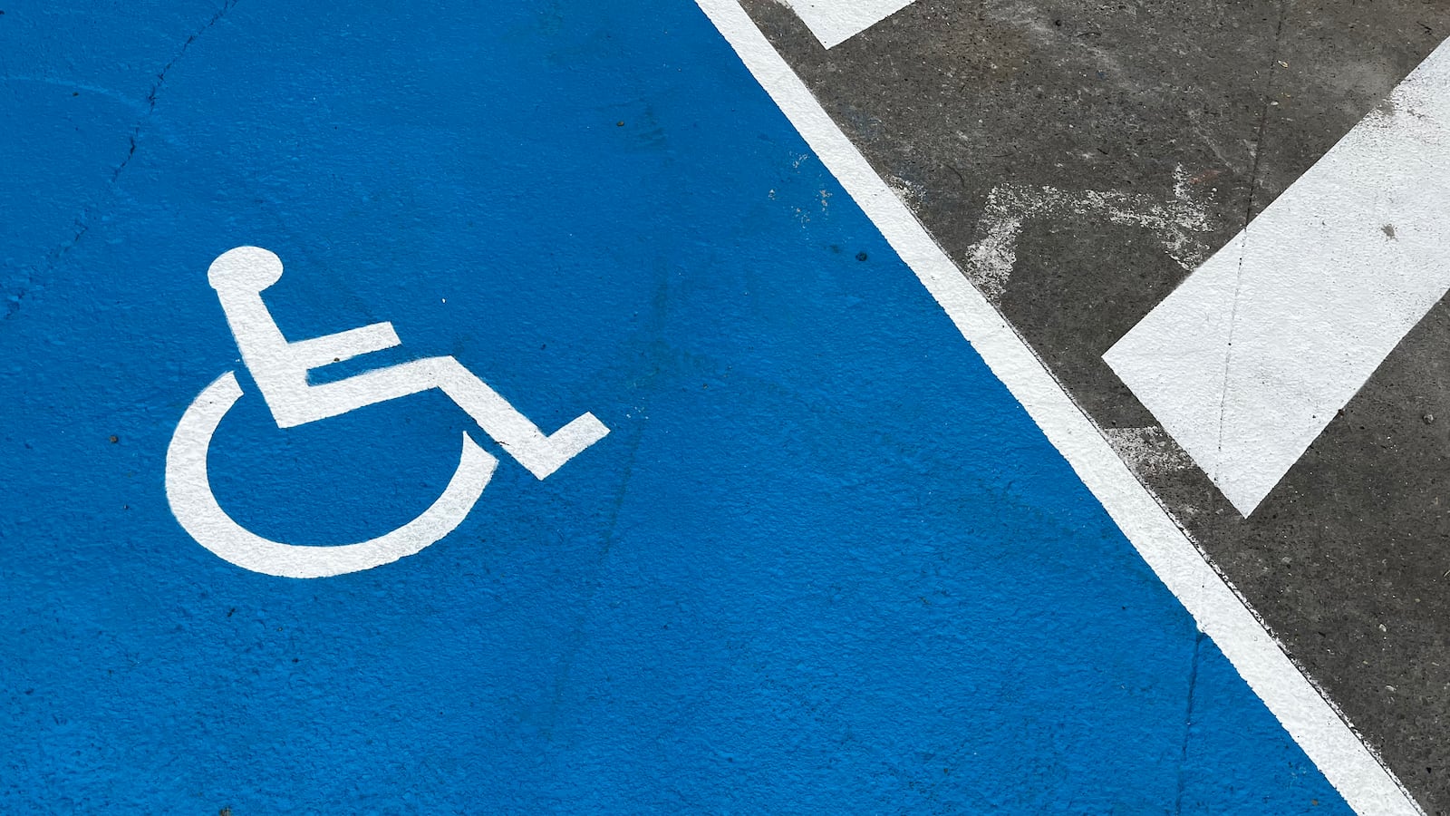A white wheelchair icon on a painted blue parking space.
