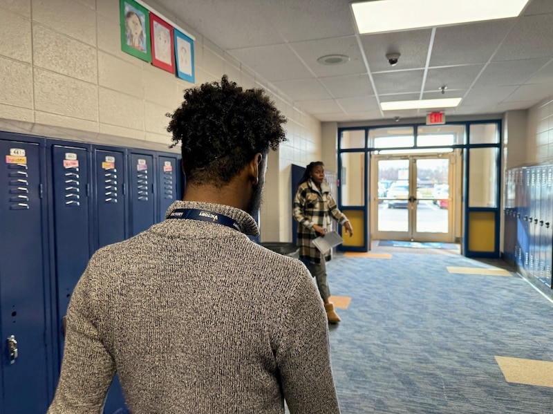 Man walks down hallway with Blue lockers and blue rug